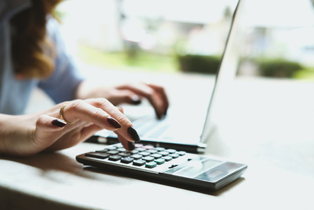 young businesswoman working with calculator, laptop computer in garden. female accountant making calculation. bookkeeper calculate budget. Savings, finance and economy conceptの写真素材