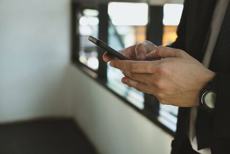 young businessman holding smartphone & using app at office. man texting message at workplace. social network communication, wireless connection, lifestyle conceptの写真素材