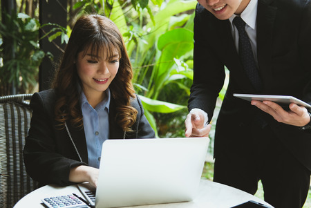 young business people having a meeting. businessman & businesswoman working with computer together at cafe. startup man & freelance woman discussing idea at coffee shop. discussion, teamwork, collaboration, corporate concept.の写真素材