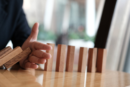 hand stopping effect of domino continuous toppled. busineeman protecting falling wood block. solution & strategy in business. problem solving conceptの写真素材