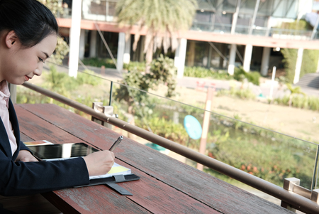 businesswoman writing note ourdoors. young female entrepreneur sitting on balcony. asian freelance woman working on terrace. people lifestyle conceptの写真素材
