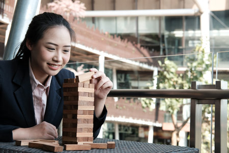 businesswoman hand placing wood block on tower. growth, risk & strategy in business.