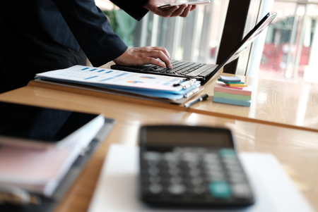 businesswoman holding mobile phone at office. young female entrepreneur using smartphone at cafe. freelance woman working with computer at coffee shop. business conceptの写真素材