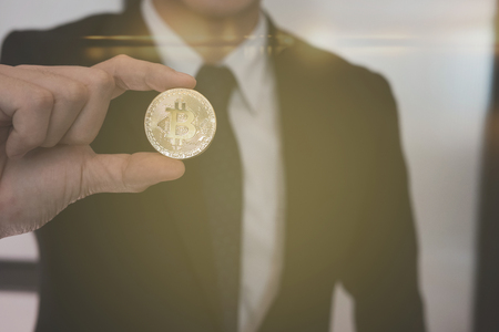 businessman in suit holding bitcoin golden coin. symbol of crypto currency digital moneyの写真素材