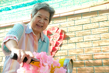 asian elder woman riding motorcycle. happy elderly female on yellow motorbike. fun mature lifestyle conceptの写真素材
