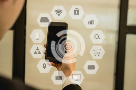 young businessman holding smartphone & using app. man texting message outdoors. social network communication, wireless connection, lifestyle concept with internet of thing iconの写真素材