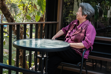 asian elder woman resting on terrace. elderly female relaxing on patio. senior leisure lifestyle at homeの写真素材