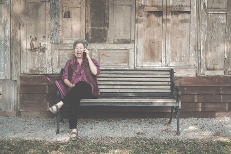 elder woman talk on mobile phone in garden. elderly female speaking on smartphone in park. asian senior have phone conversationの写真素材