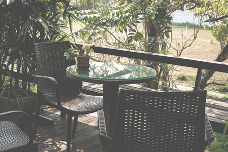 round wood table on terrace of house. wicker rattan chair on patio near garden at home. relaxing lifestyle concept.の写真素材