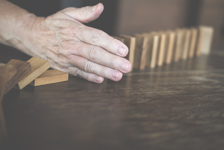 hand stopping effect of domino continuous toppled. woman protecting falling wood block. solution & strategy in business. problem solving conceptの写真素材