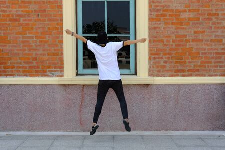backside of woman jumping with happiness outdoors.の写真素材