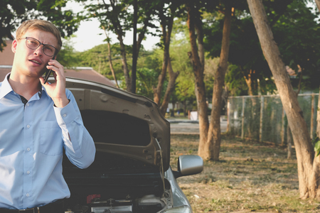male agent use smart phone for claiming auto insurance. caucasian man calling for assistance for car damaged by traffic accidentの写真素材