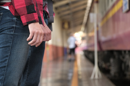 man and woman with backpack waiting for train at railway station. loving couple traveler travel together on holidayの写真素材