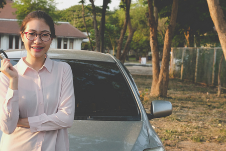 happy woman buying new car. asian female driver showing car keyの写真素材