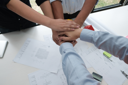 architect & customer joining hands at workplace. Engineer put hand together with partner for successful deal in building project development. business teamwork conceptの写真素材