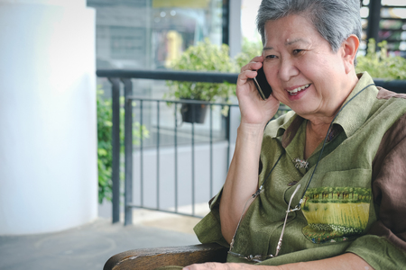 elder woman talk on mobile phone. elderly female speaking on smartphone. senior have phone conversation outdoorの写真素材