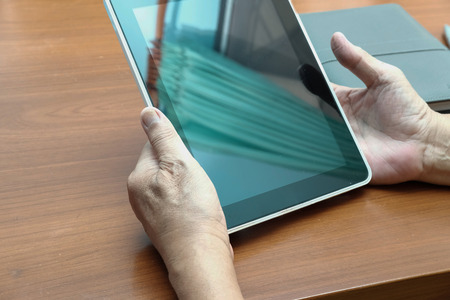 man working with digital tablet at office. hand holding touchpad at workplaceの写真素材