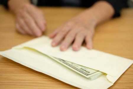 woman offering envelope with money banknote. hand giving cash banknote - bribery, corruption, venality conceptの写真素材