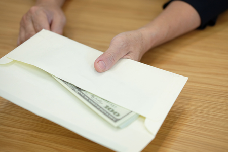 woman offering envelope with money banknote. hand giving cash banknote - bribery, corruption, venality conceptの写真素材