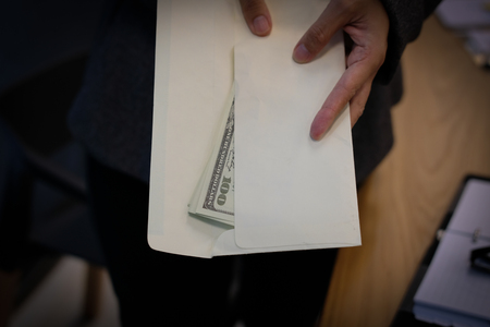 woman offering envelope with money banknote. hand giving cash banknote - bribery, corruption, venality conceptの写真素材