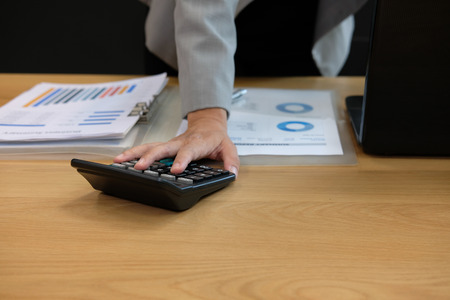 financial adviser working with calculator, business document & computer at office. accountant doing accounting & calculating revenue & budget. bookkeeper making calculation. finance & economy conceptの写真素材