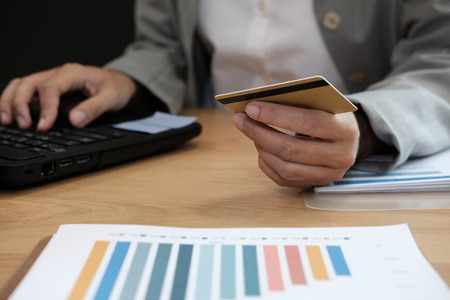 woman holding credit card using computer for online shopping. businesswoman purchase product from internet, make payment on bank website at workplaceの写真素材