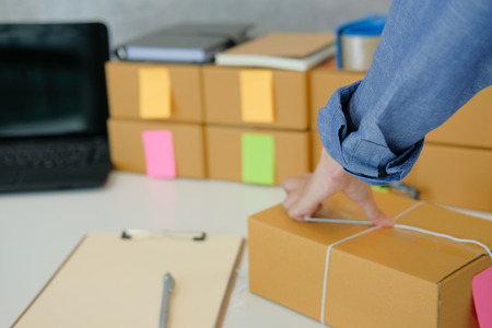 startup small business owner packing cardboard box at workplace. freelance woman entrepreneur seller prepare product parcel box for deliver to customer. Online selling, e-commerce conceptの写真素材