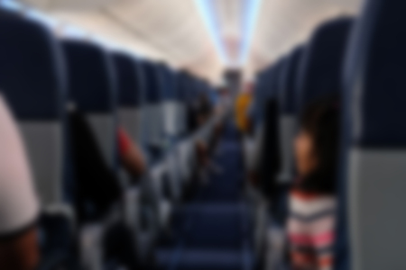 passenger sit on seat in airplane.  aisle in aeroplane interior. blurry defocused backgroundの写真素材