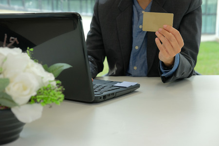 man holding credit card using computer for online shopping. businessman purchasing product from internet, make payment on bank website at workplaceの写真素材