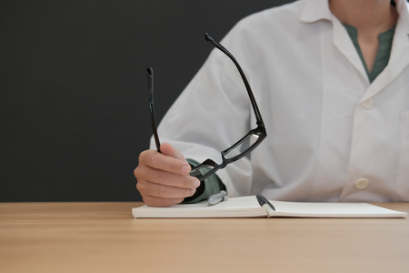 doctor holding eyeglasses at clinic. pharmacist with notebook at medical officeの写真素材