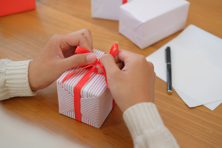 man wearing cream sweater wrapping christmas gift present box. xmas new year holiday celebration.の写真素材