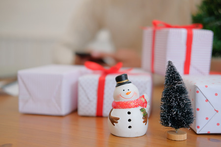 man wearing cream sweater using mobile smart phone with christmas decoration. xmas new year holiday celebration.の写真素材