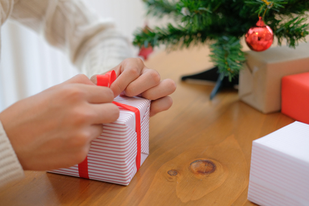 man wearing cream sweater wrapping christmas gift present box. xmas new year holiday celebration.の写真素材