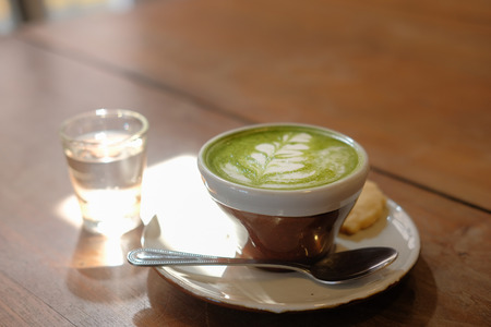 hot matcha green tea with leaves latte art on wooden tableの写真素材