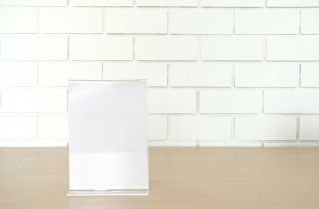 white label in cafe. display stand for acrylic tent card near white brick wall. mockup menu frame on table in restaurant. space for textの写真素材