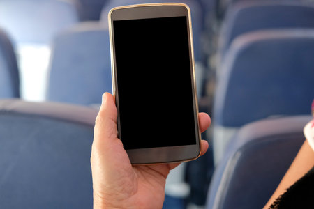 hand holding mobile smart phone on airplane