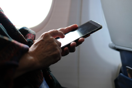 hand holding mobile smart phone on airplaneの写真素材