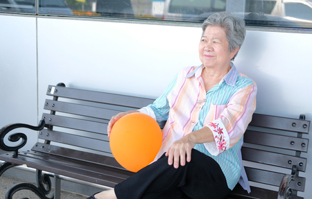 old elder woman holding balloon. asian elderly female relaxing outdoors. senior leisure lifestyleの写真素材