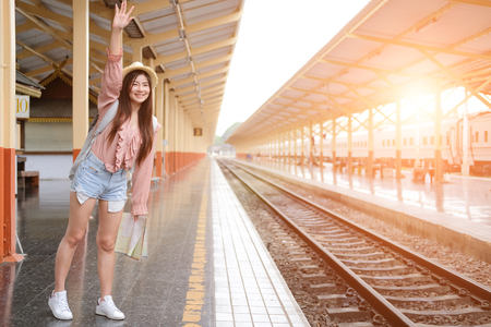 woman traveler with backpack map raising waving hand at train station. trip journey travel conceptの写真素材