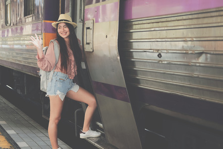 young woman tourist traveler stepping up to train on railway at train station. Travel journey trip conceptの写真素材