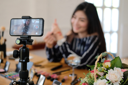 beauty blogger live broadcasting cosmetic makeup tutorial on social media. vlogger recording vlog video. influencer marketingの写真素材