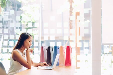 woman using computer & credit card for online payment with shopping bags on table. consumerism lifestyle conceptの写真素材