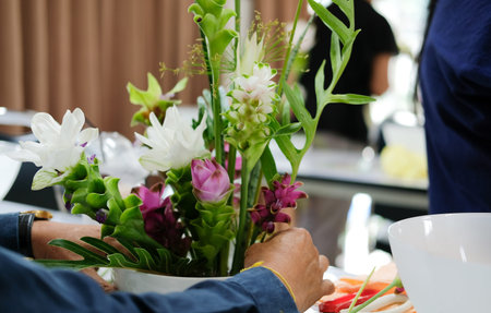 florist arranging flower bouquet in vase. people in floristry class course workshop