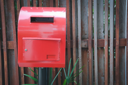 red post box mailbox beside wooden fence