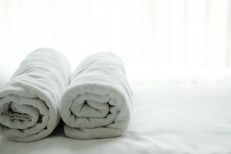 white towel on bed with see through curtain background. hotel bedroom interiorの写真素材