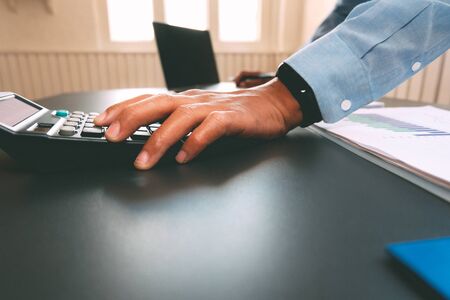 financial adviser working with calculator at office. accountant doing accounting & calculating revenue & budget. bookkeeper making calculation. finance & economy conceptの写真素材