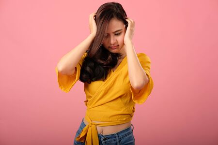 studio portrait of asian woman in casual clothing feeling sad unhappy stressed depressedの写真素材