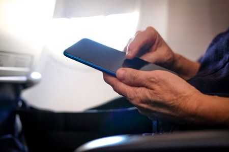 woman traveler using smartphone in airplane. passenger holding mobile phone in aircraft. travel and...
