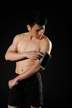 portrait of athletic muscular bodybuilder man with smart mobile phone armband listening to music....