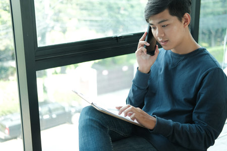 male freelancer talking on mobile smart phone at office. young asian freelance man female...